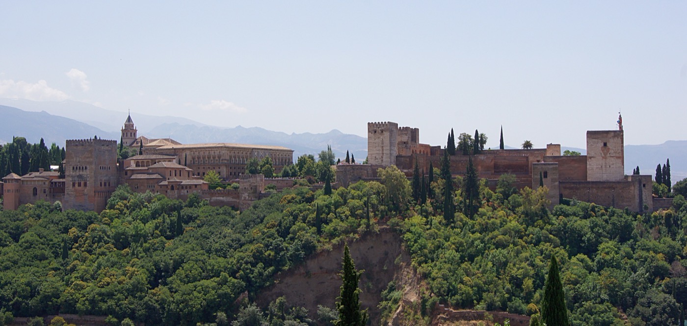 The Alhambra complex on its wooded hill in Granada, with hazy mountain ridges behind it